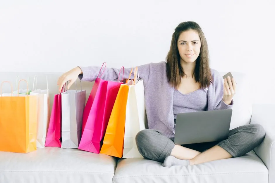 Shopper relaxing on a sofa with a laptop and shopping bags, illustrating an online stacking session