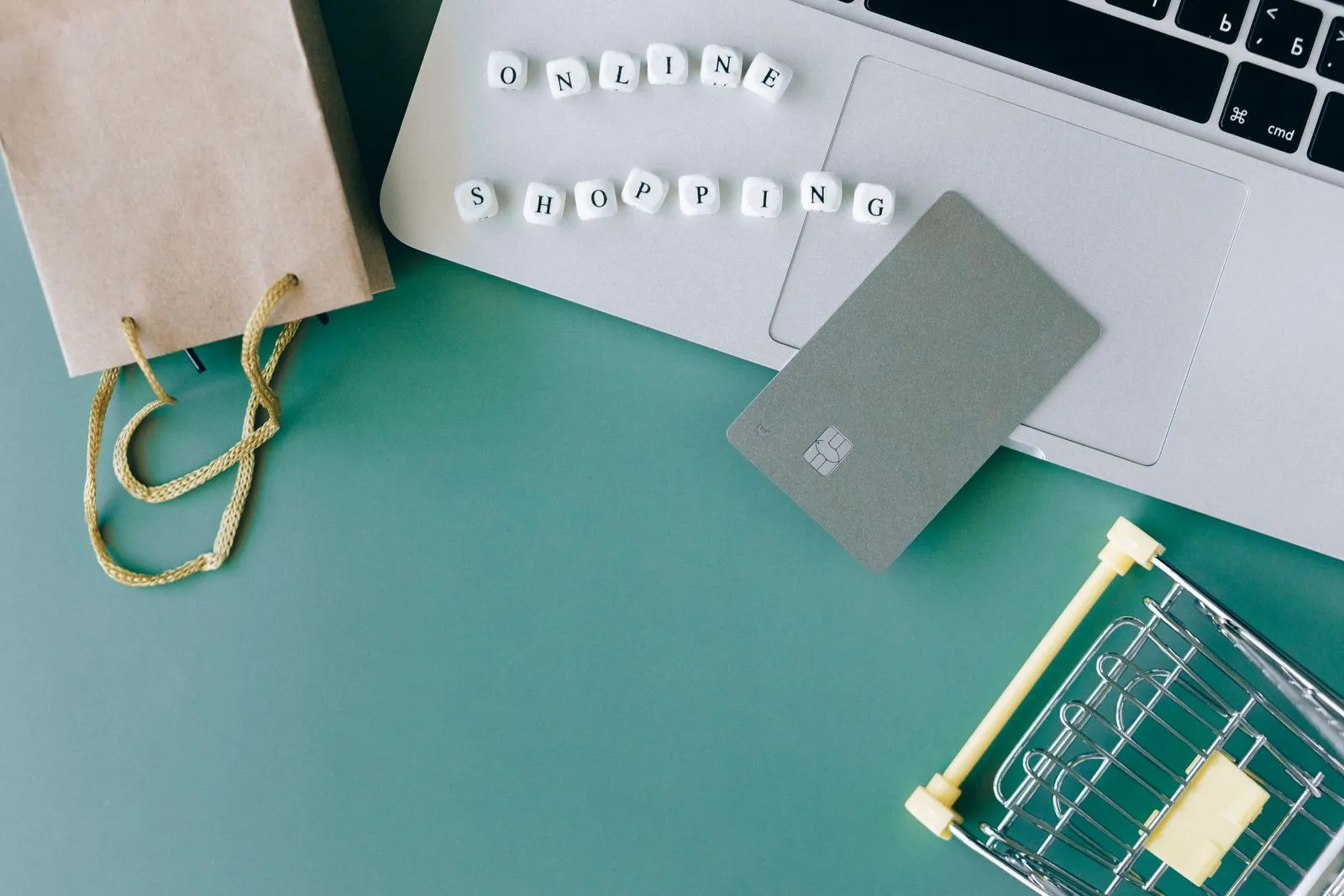 Laptop, bank card, and shopping cart illustrating an online checkout, used to represent coupon and cashback stacking