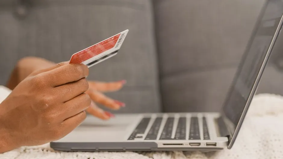 Close-up of a person entering a promo code and paying with a card during an online checkout